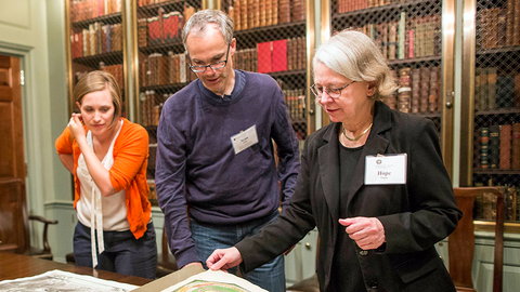 Three people leafing through a book.