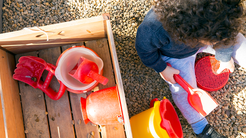 Child playing with a bucket and shovel in a playground.