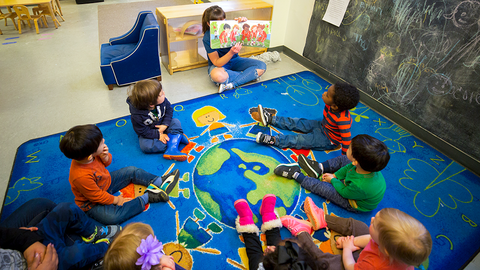 Teacher reading a book to a group of children at a Harvard child care center.