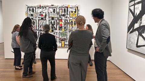 A group of faculty members in front of a large painting at the Harvard Art Museums.