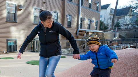 A mother and child holding hands in a playground.