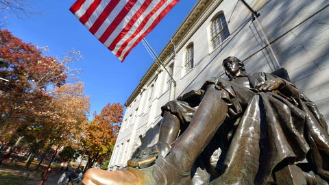 The John Harvard statue on a bright sunny day in Harvard Yard