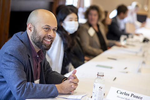 New faculty member seated at table and smiling.