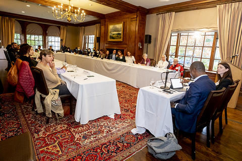 New faculty attendees seated around a U shape table listening to faculty panelists.