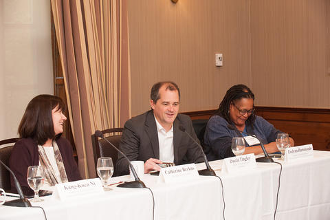 The four panelists, seated, address the audience.