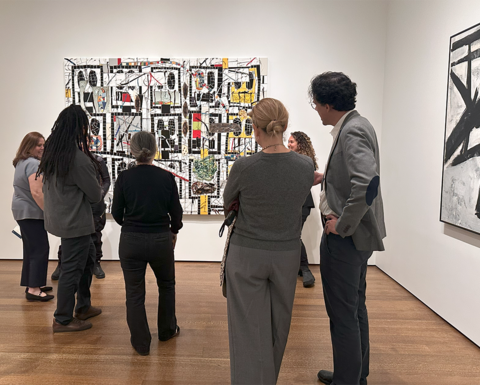 A group of faculty members in front of a large painting at the Harvard Art Museums.